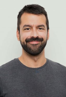 Man with mustache and trimmed beard smiles, happy with his Invisalign NYC